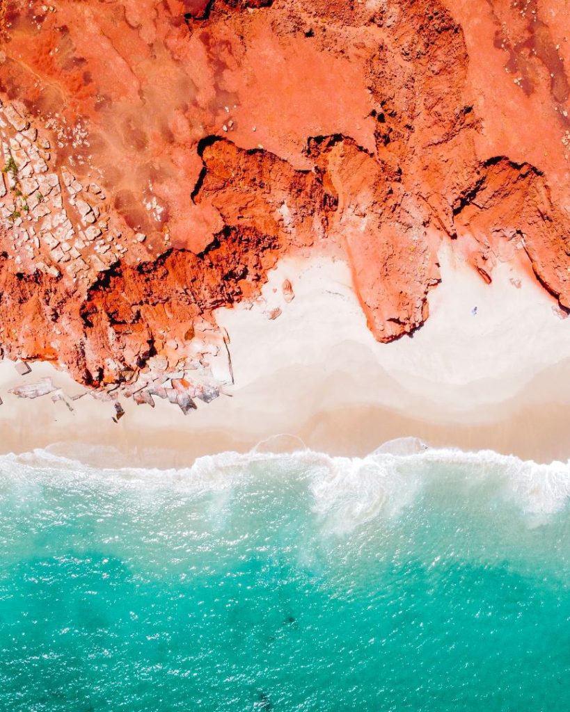 Aerial view of red cliffs meeting white sand beaches and turquoise ocean at Cape Leveque on the Dampier Peninsula.