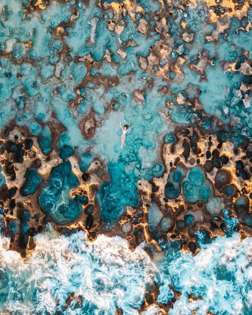 Aerial view of Coconut Well rockpools, with turquoise water filling rocky formations near the shore.