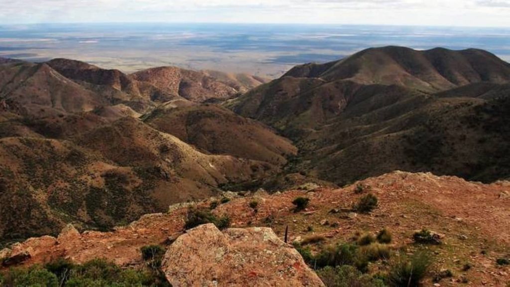 A sweeping view of rugged hills and valleys from the summit of Dutchman’s Stern in the Flinders Ranges, South Australia, with vast plains in the distance.