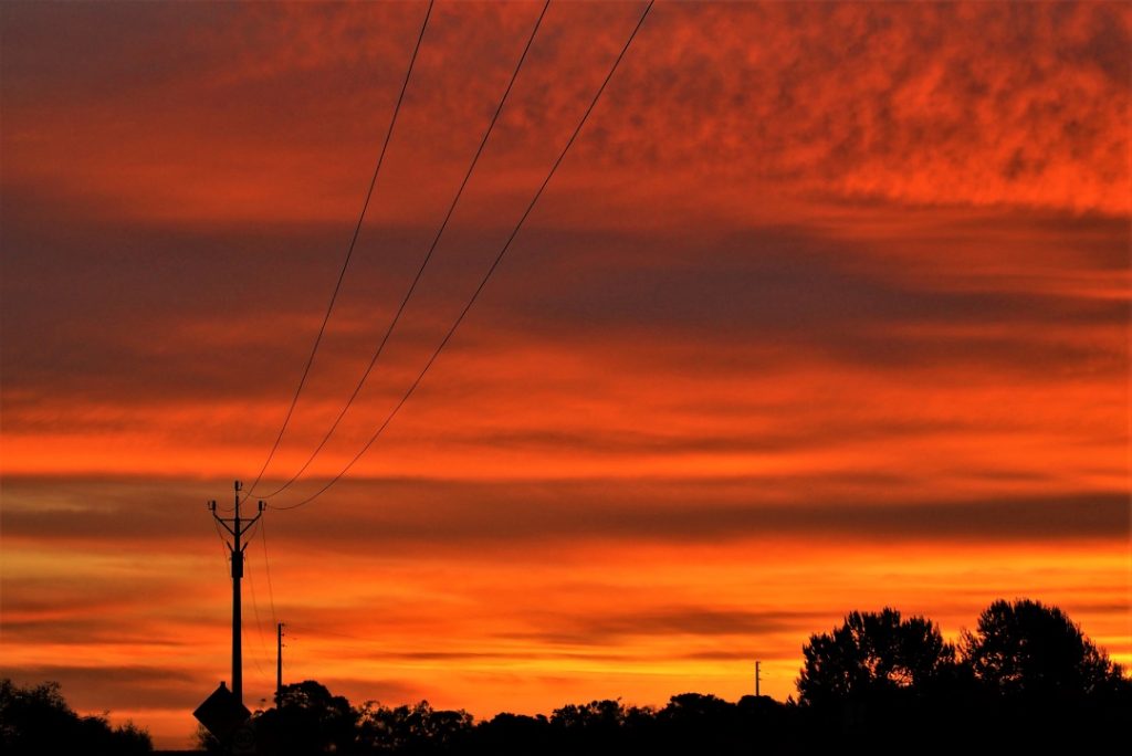 A striking sunset at Sultana Point, Yorke Peninsula, South Australia, with powerlines silhouetted against a glowing orange sky.