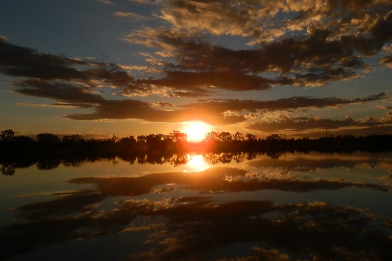 A serene sunset over Lake Lascelles in Hopetoun, Victoria, Australia, with reflections of trees and clouds on the still water.