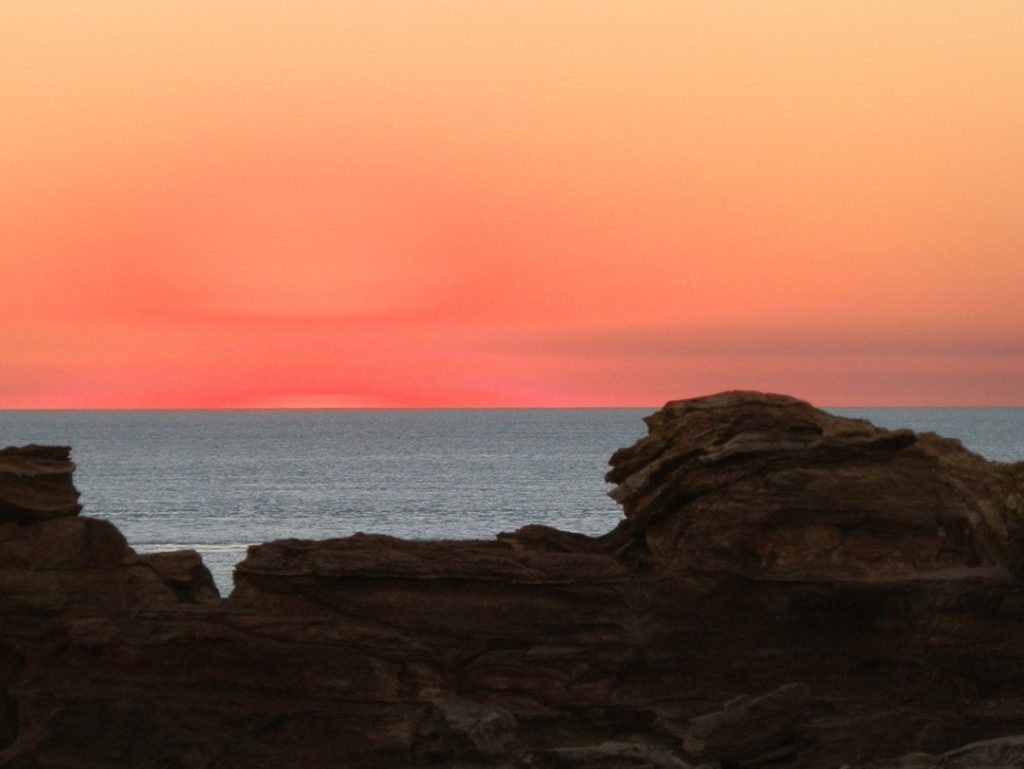 A soft pastel sunset at Gantheaume Point in Broome, Western Australia, with rugged rock formations framing the view.