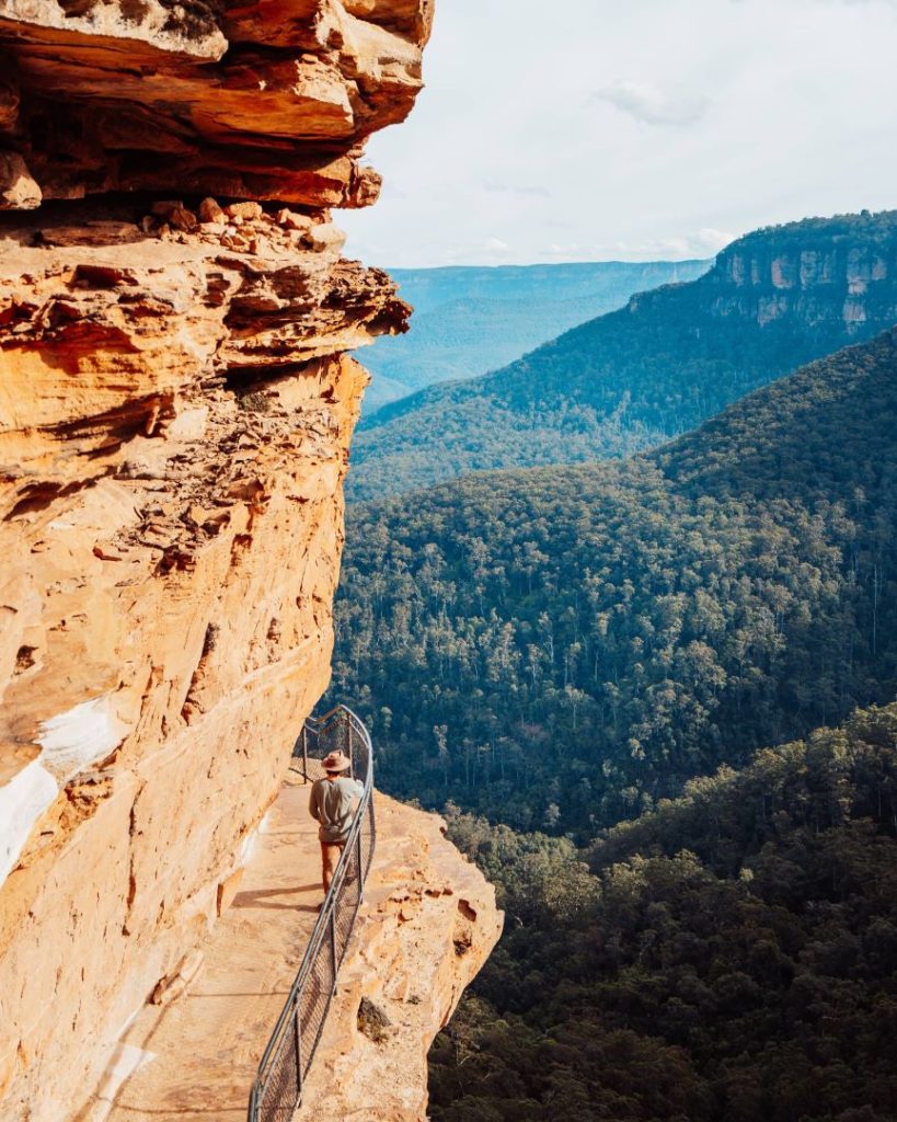 A hiker explores the narrow Cliff Walk at Wentworth Falls, framed by dramatic cliffs and forested valleys. Winter offers clear vistas and fewer crowds for a peaceful adventure.