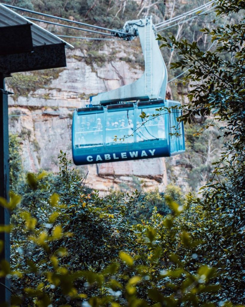 The Scenic World Cableway gliding through the lush forested cliffs of the Blue Mountains, offering unique perspectives on great Blue Mountains tours. A must-try experience for visitors.