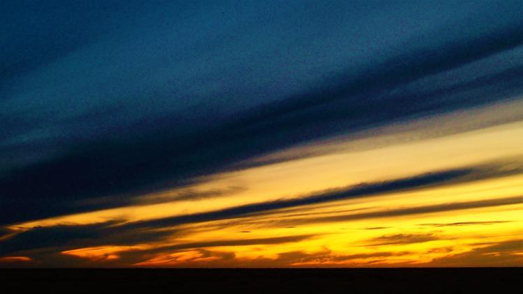 A Deniliquin sunset in New South Wales, Australia, with streaks of deep blue and golden yellow spreading across the expansive sky.