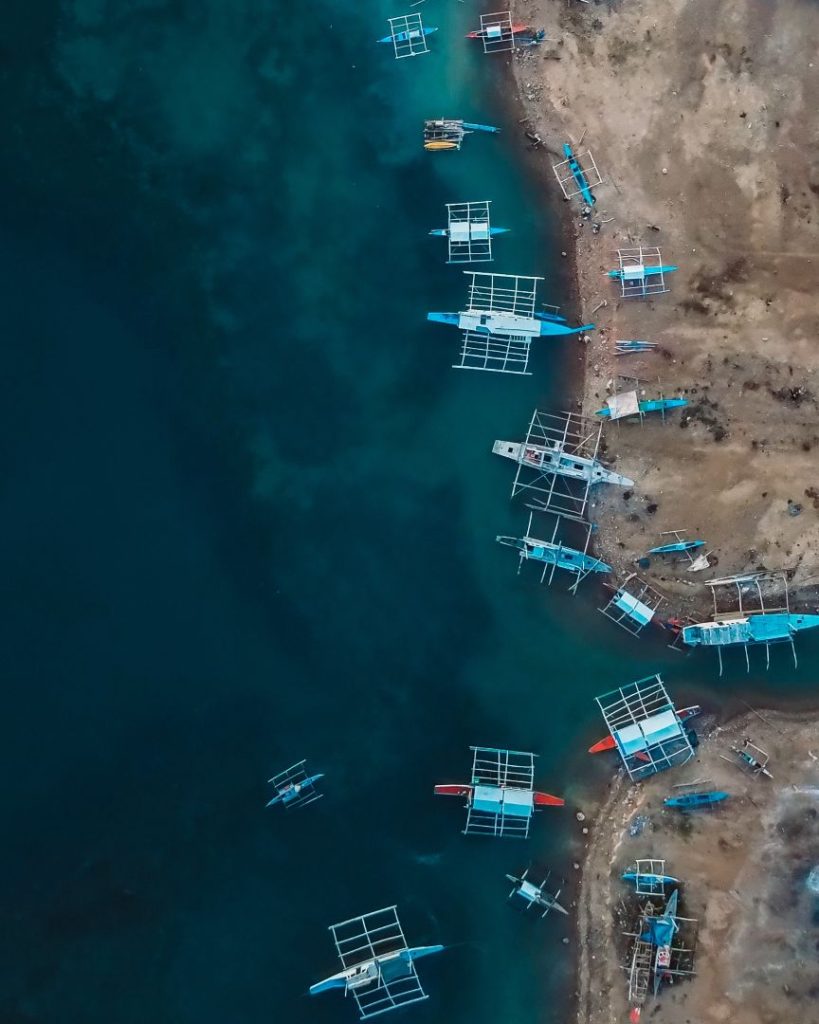 Traditional Filipino boats line the shoreline of Moalboal, seen from above—coastal adventures in Moalboal are a must-do among things to do in Cebu.