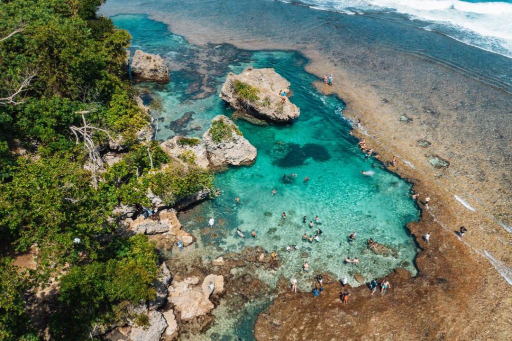 Aerial view of Magpupungko Beach in Siargao, showing its famous tidal pools surrounded by rock formations and crystal-clear waters. A must-see destination in the Philippines, ideal for swimming and cliff-jumping.
