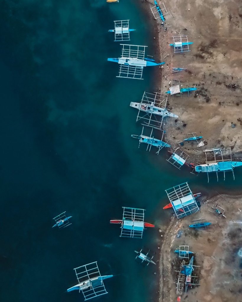 Aerial view of traditional Filipino outrigger boats (bancas) floating near the shoreline in Moalboal, Cebu. This must-see spot in the Philippines is famous for its marine biodiversity and island-hopping adventures.