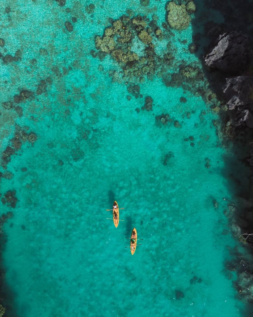 Overhead view of two yellow kayaks floating on crystal-clear teal water at Big Lagoon—Tour A, often considered the best tour in El Nido, offers this iconic experience.
