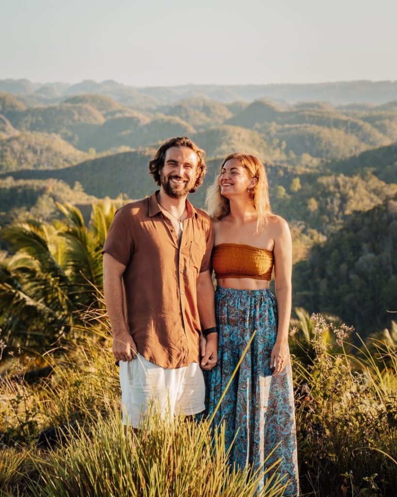 A couple stands smiling in front of the lush, rolling Chocolate Hills in Bohol—while not in Cebu, exploring nearby Bohol is a popular addition to things to do near Cebu.