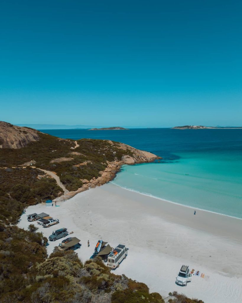 Aerial view of 4WDs parked at Wharton Beach in Esperance, where white sand meets crystal-clear water on the Perth to Albany road trip.