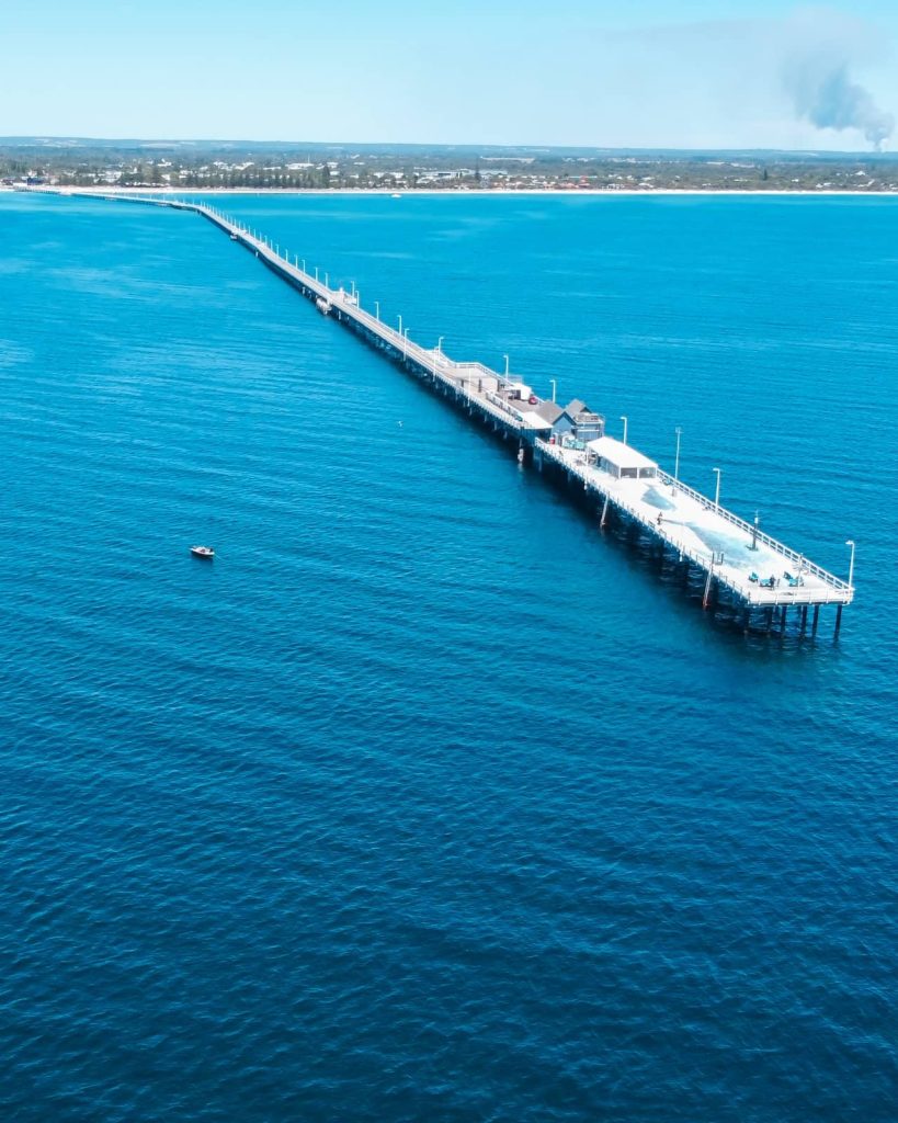 Drone view of Busselton Jetty stretching out into vivid blue water, one of the iconic stops along a Perth to Albany road trip.