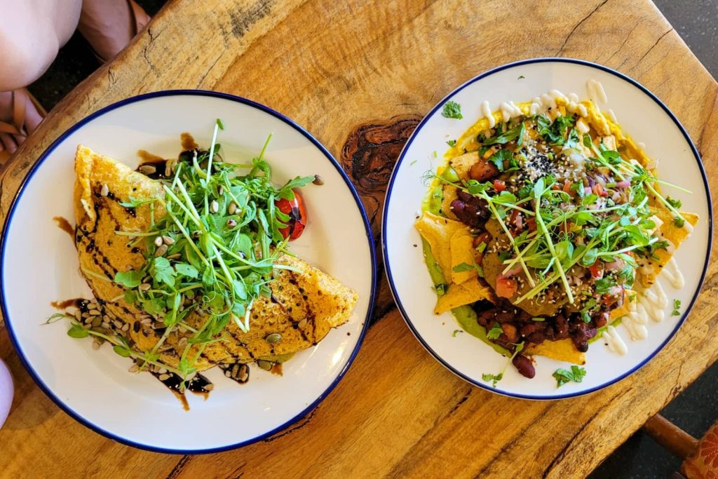 Overhead shot of two colourful vegetarian meals topped with microgreens, served in Albany during a food stop on a Perth to Bremer Bay road trip.