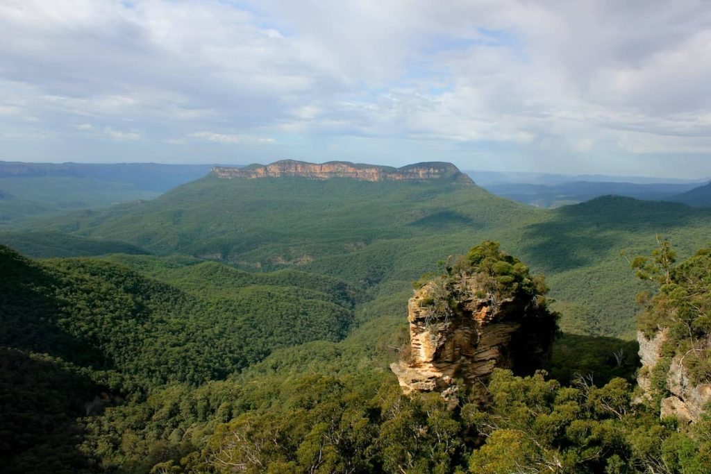 Scenic view of the Jamison Valley in the Blue Mountains, with dense forest, sandstone ridges, and Mount Solitary in the distance.
