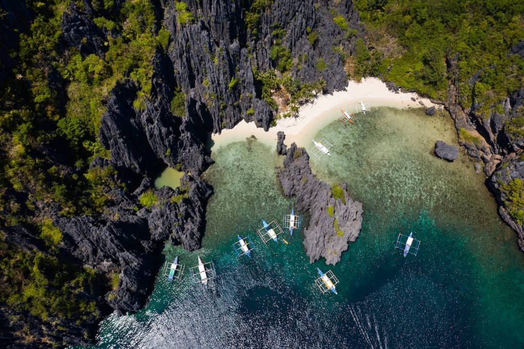 Aerial view of boats anchored outside the hidden beach entrance to Secret Lagoon in El Nido