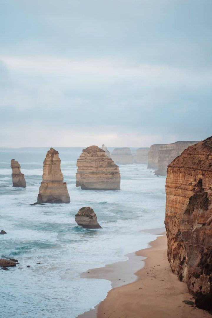 Sea stacks rise from the surf along a golden beach at the Twelve Apostles, a highlight of most great ocean road itineraries for its striking rock formations.