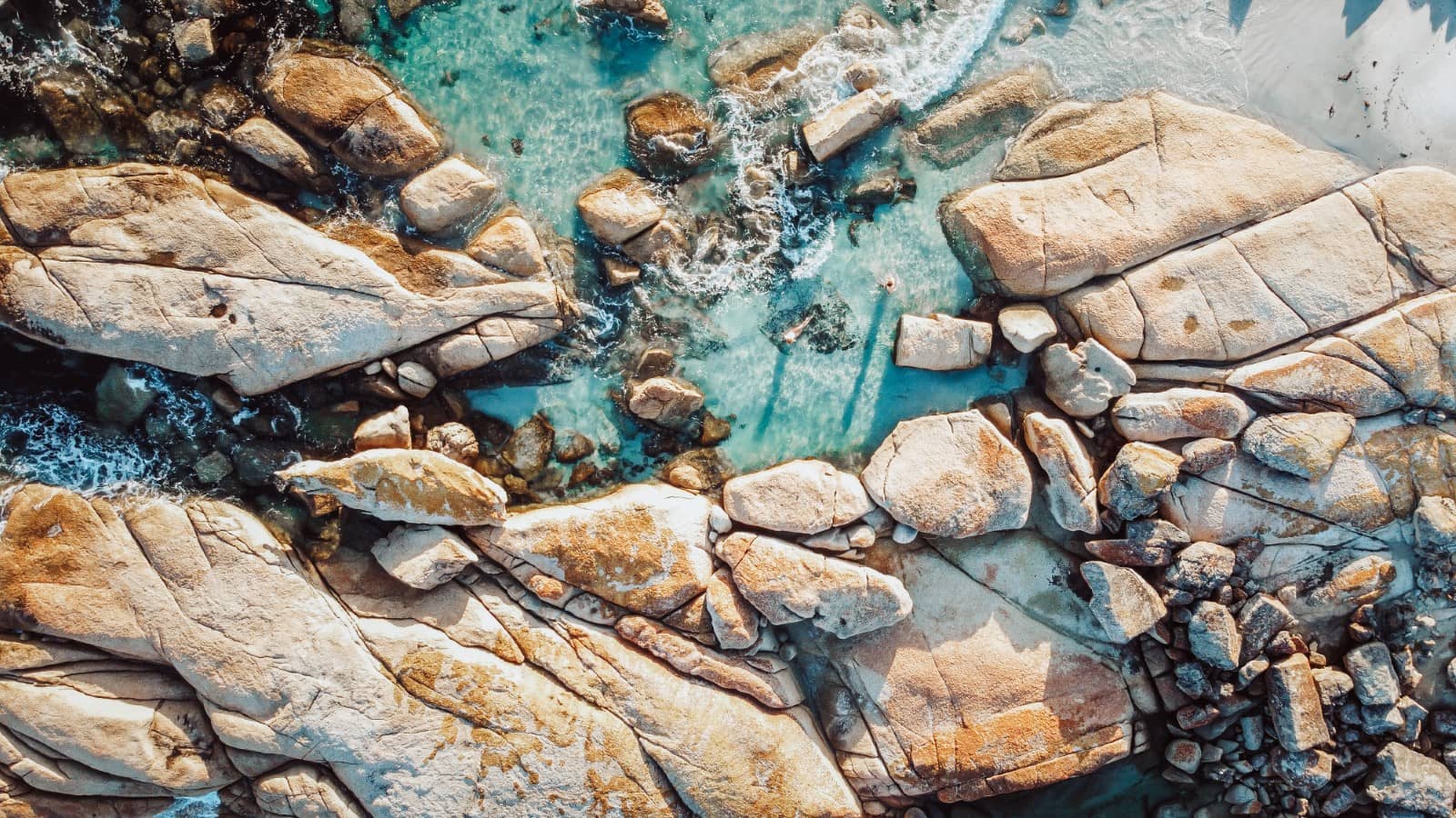 Aerial view of binalong bay in bay of fires, tasmania, with its massive orange-tinged granite boulders and clear turquoise water, a highlight on a 7 day Tasmania road trip itinerary.